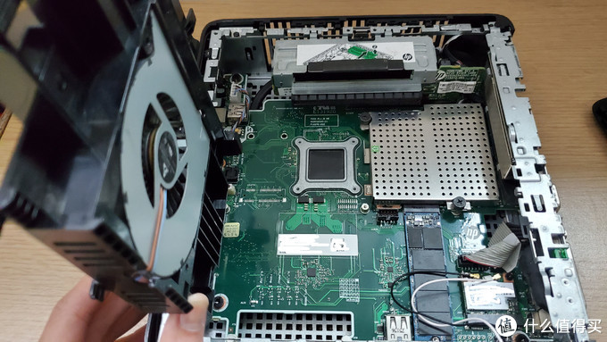 拿起风扇后就可以看到真正的机箱内部,顶部的PCIE 4X转PCIE 16X,中间的CPU,CPU隔壁的金属罩是2根内存条的插槽,右下方的M2固态和无线网卡